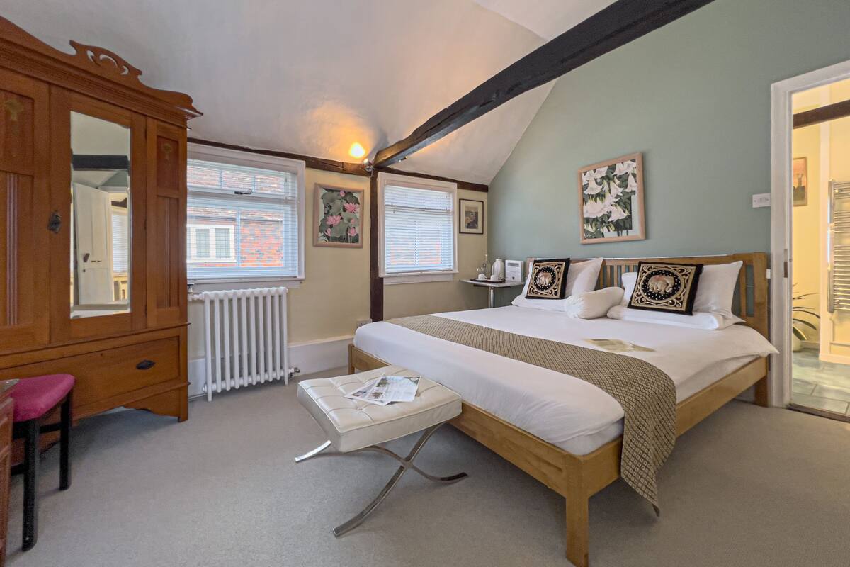 A bedroom with a bed, a wooden wardrobe, a small table, and a window.