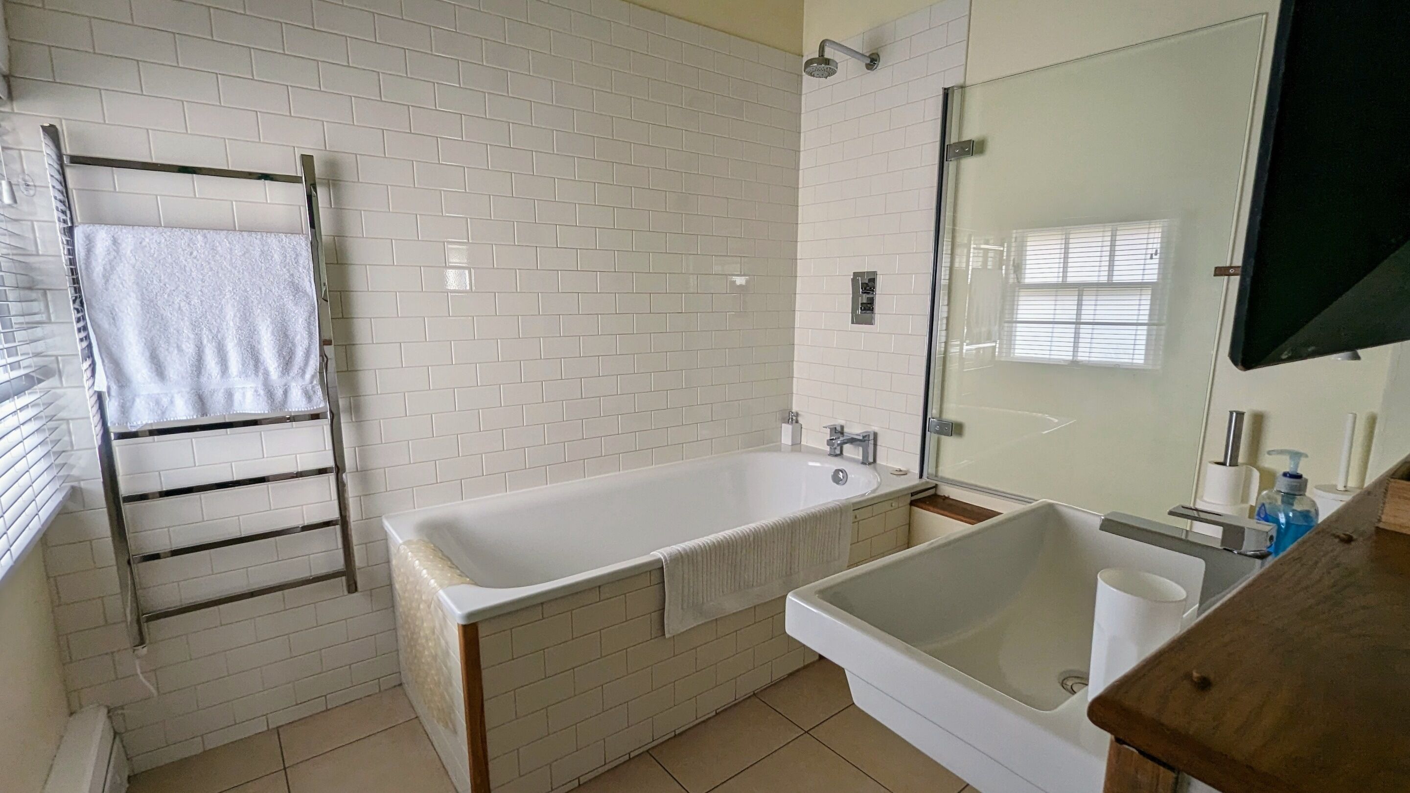 A bathroom with a bathtub, a shower, and a sink. There is a towel rack and a mirror above the sink.
