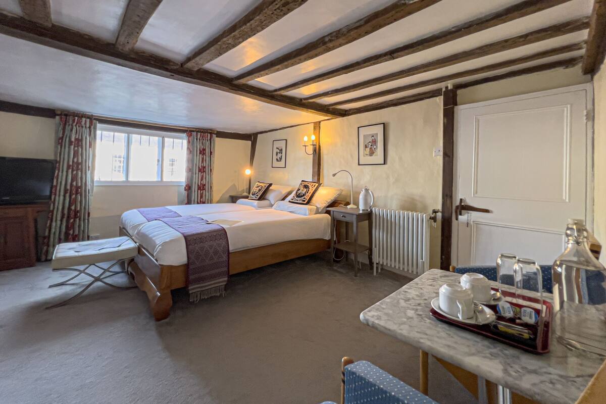 A cozy hotel room with a large bed, a small table with tea set, a radiator, and a television.