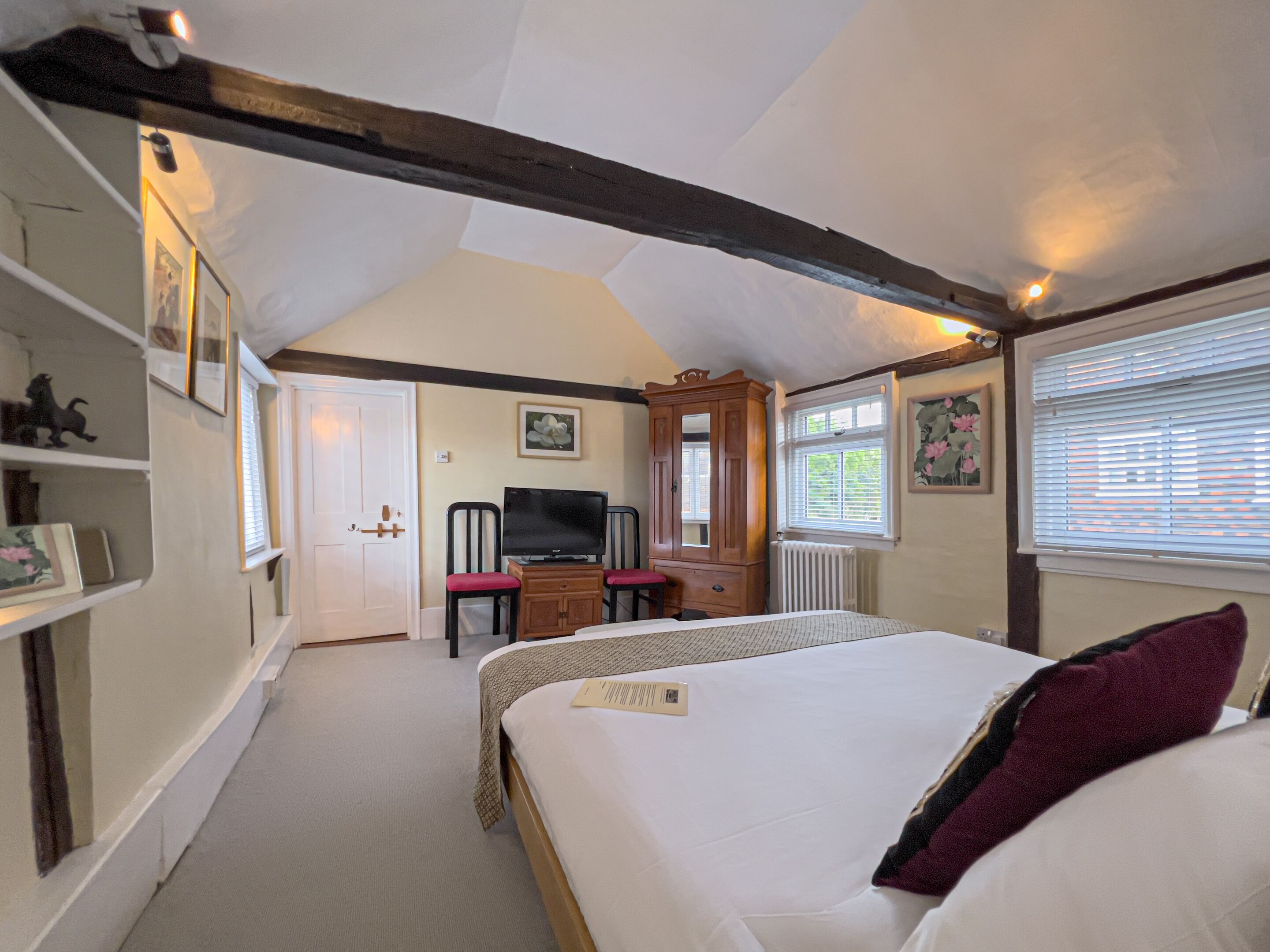 A bedroom with a bed, a television, a desk with a chair, and a wardrobe.