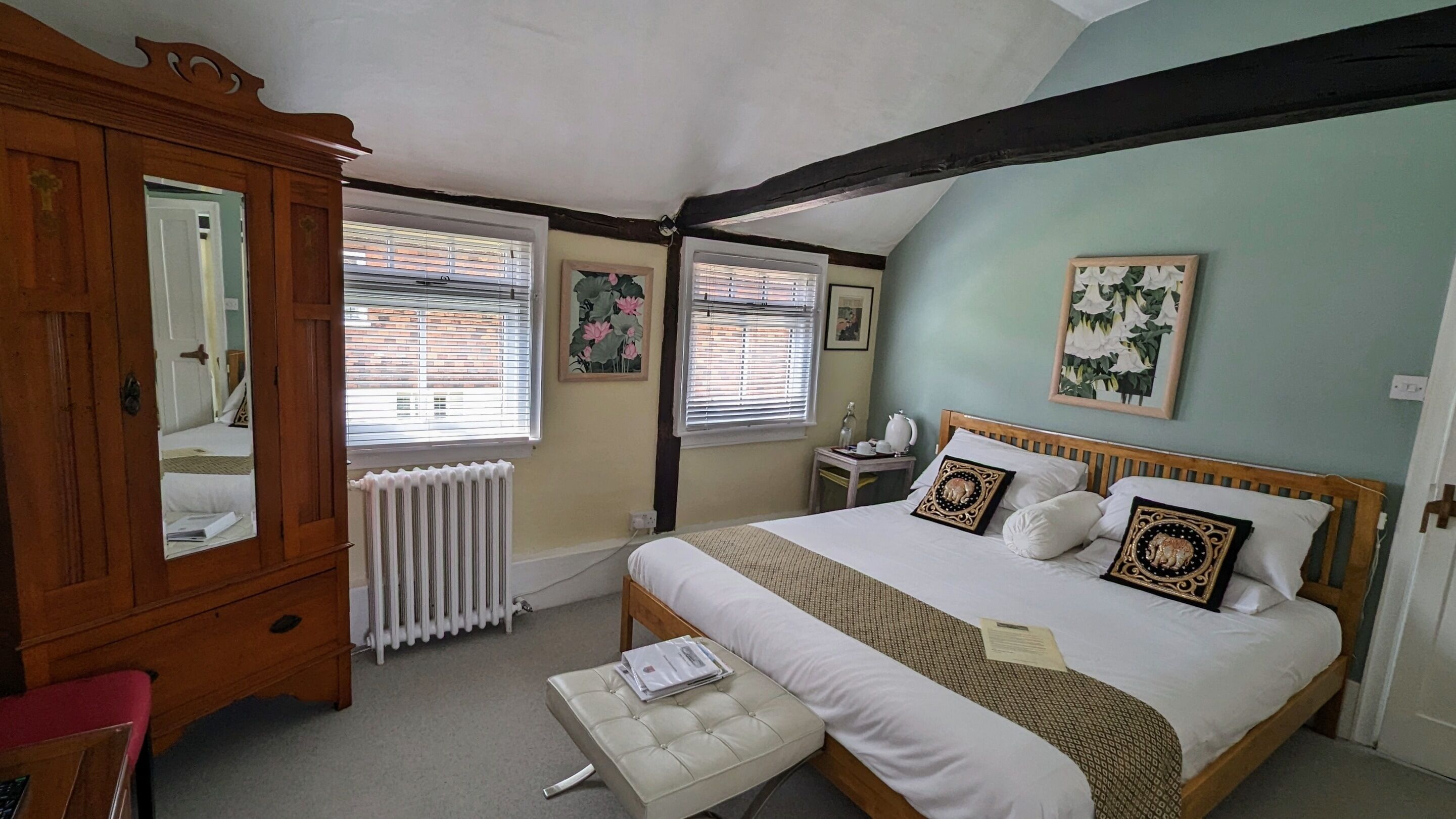 A bedroom with a wooden bed, a bedside table, a mirror, and a radiator.