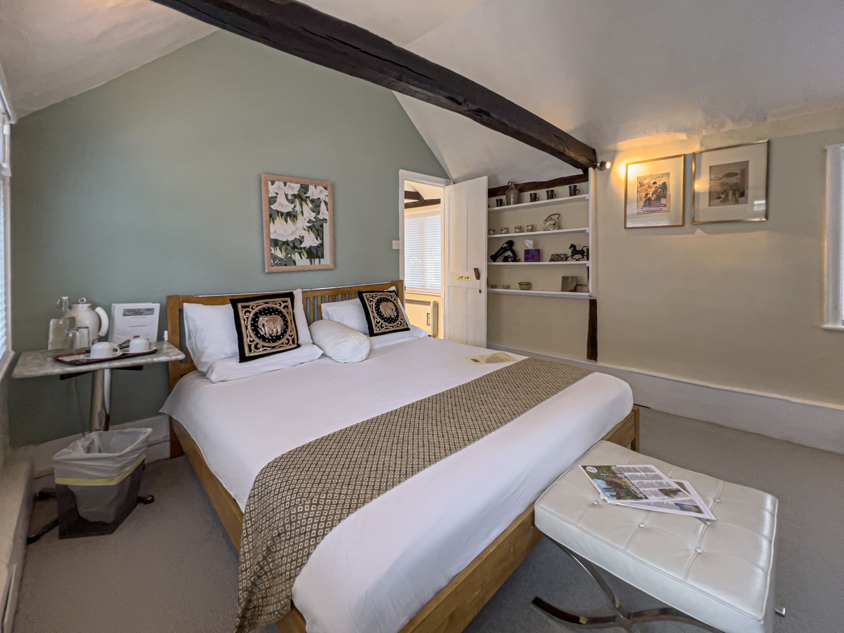 A neatly arranged bedroom with a bed, bedside table, and a reading area.