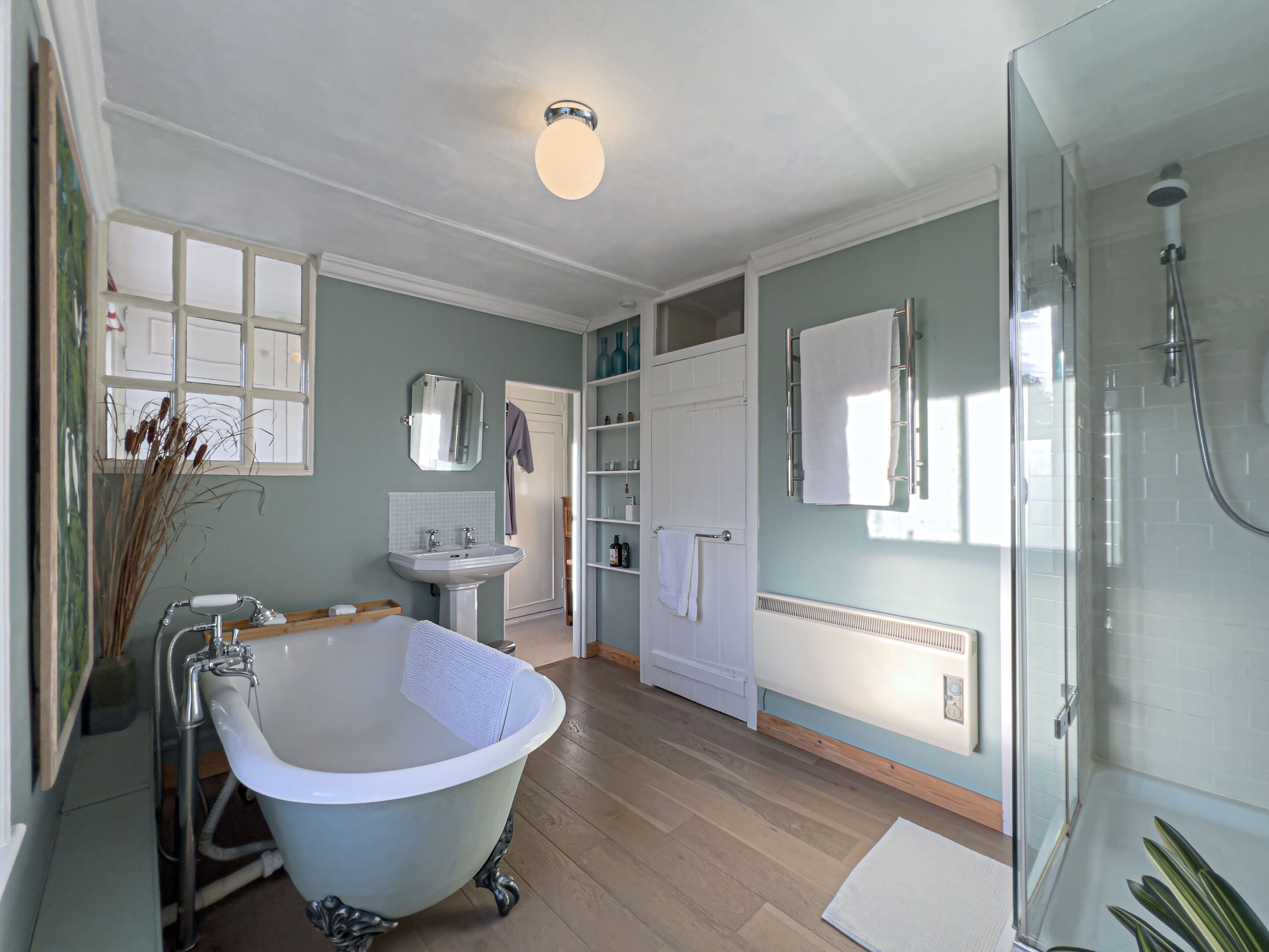A bathroom with a freestanding bathtub, a sink, a glass-enclosed shower, and a towel rack.