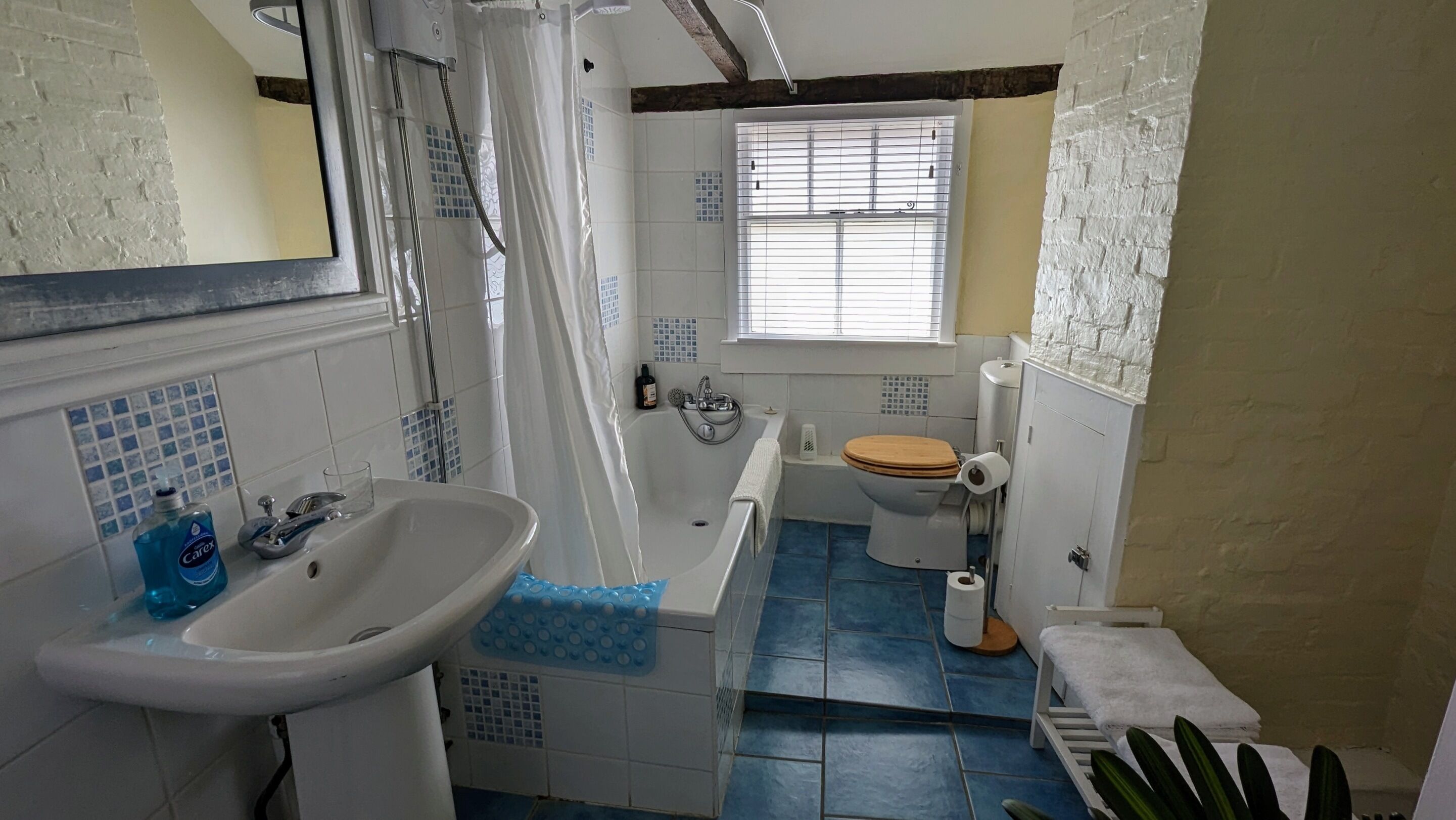 A bathroom with a bathtub, a sink, a toilet, and a window.
