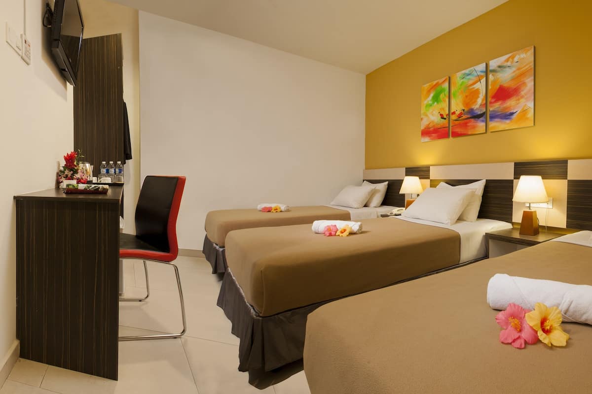 A hotel room with two beds, a desk, and a chair. There are towels and flowers on the beds.
