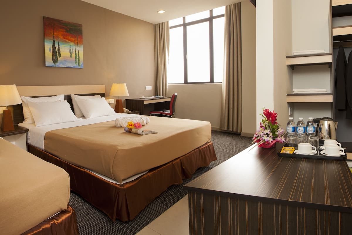 A hotel room with two beds, a desk, a minibar, and a window.