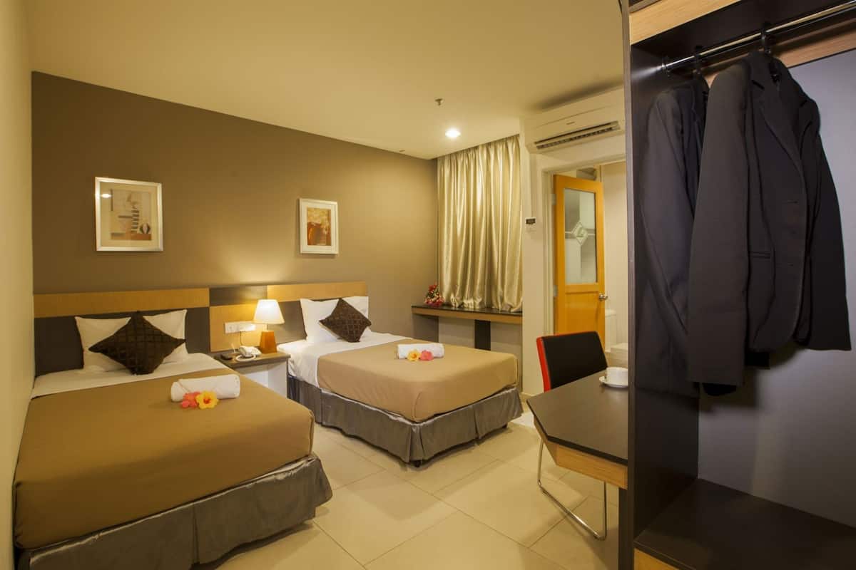 A hotel room with two beds, a desk, and a wardrobe.