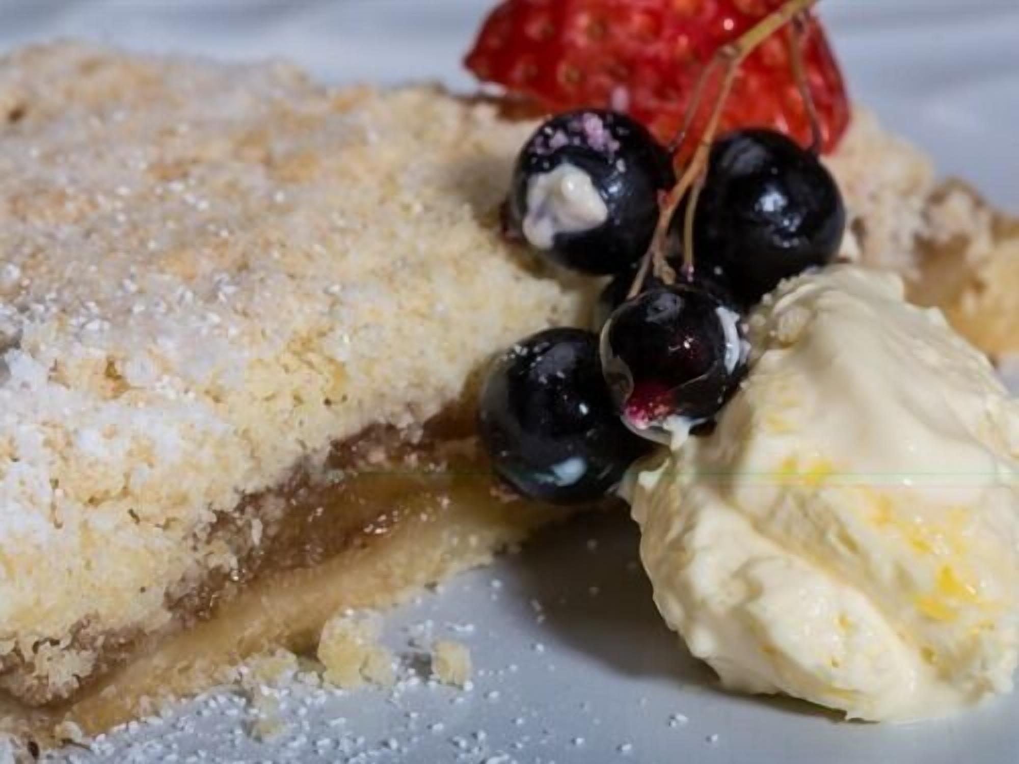 A dessert with a crumbly topping, cherries, and a scoop of ice cream.