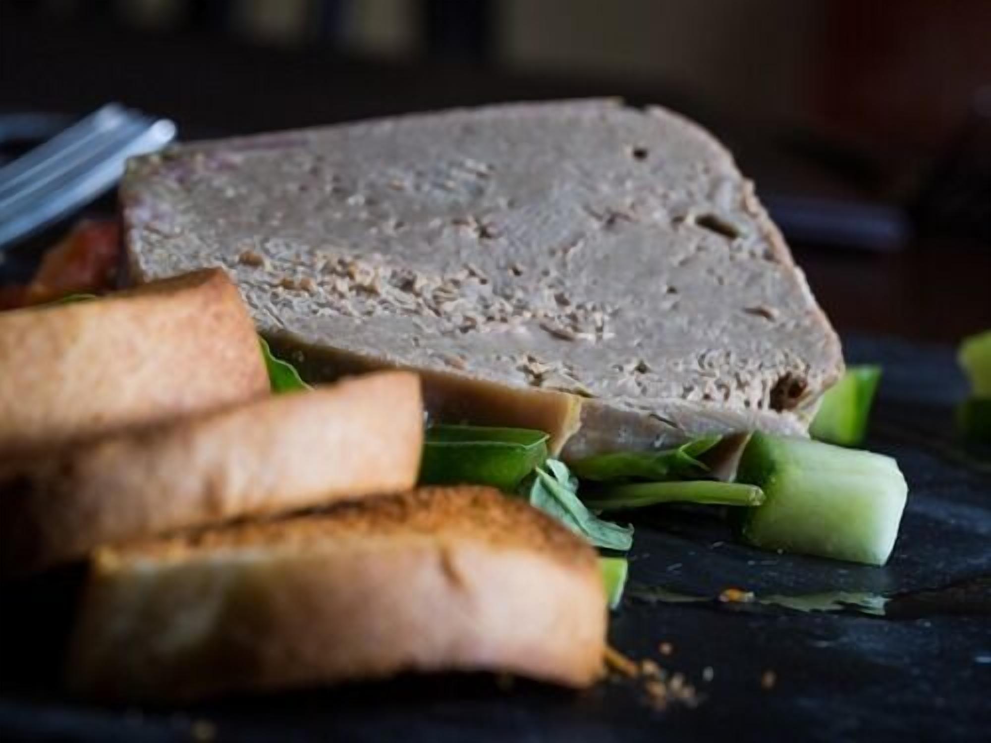 Une tranche de pain de viande accompagnée de légumes verts et de pain.