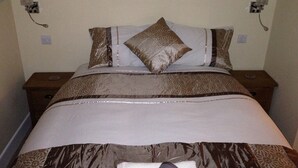 A neatly made bed with patterned bedding and two bedside tables with lamps. - Mildmay Arms (Yeovil)