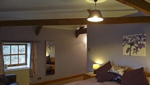 A bedroom with a bed, a nightstand, a lamp, a window, and a mirror.