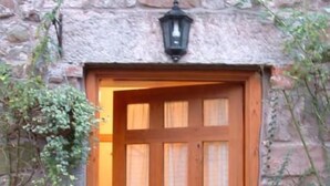 A wooden door with a glass panel, set in a stone wall with a lantern above.
