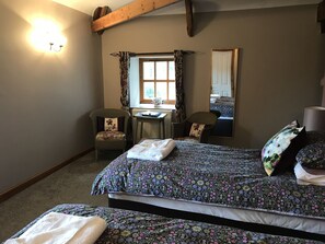 A bedroom with two beds, a desk, and two chairs.