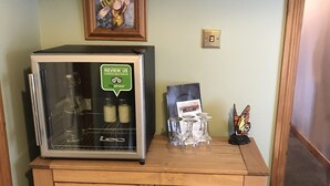 A kitchenette with a coffee machine, a framed artwork, and a small statue on a wooden counter.