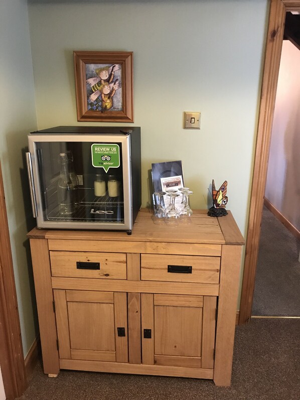 A kitchenette with a coffee machine, a framed artwork, and a small statue on a wooden counter.