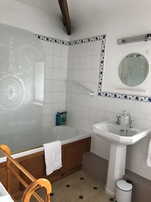 A bathroom with a bathtub, a sink, a mirror, and a toilet.