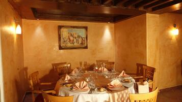 Comedor con una mesa redonda dispuesta para cuatro personas, sillas de madera, un cuadro en la pared y dos luces fijadas a la pared.
