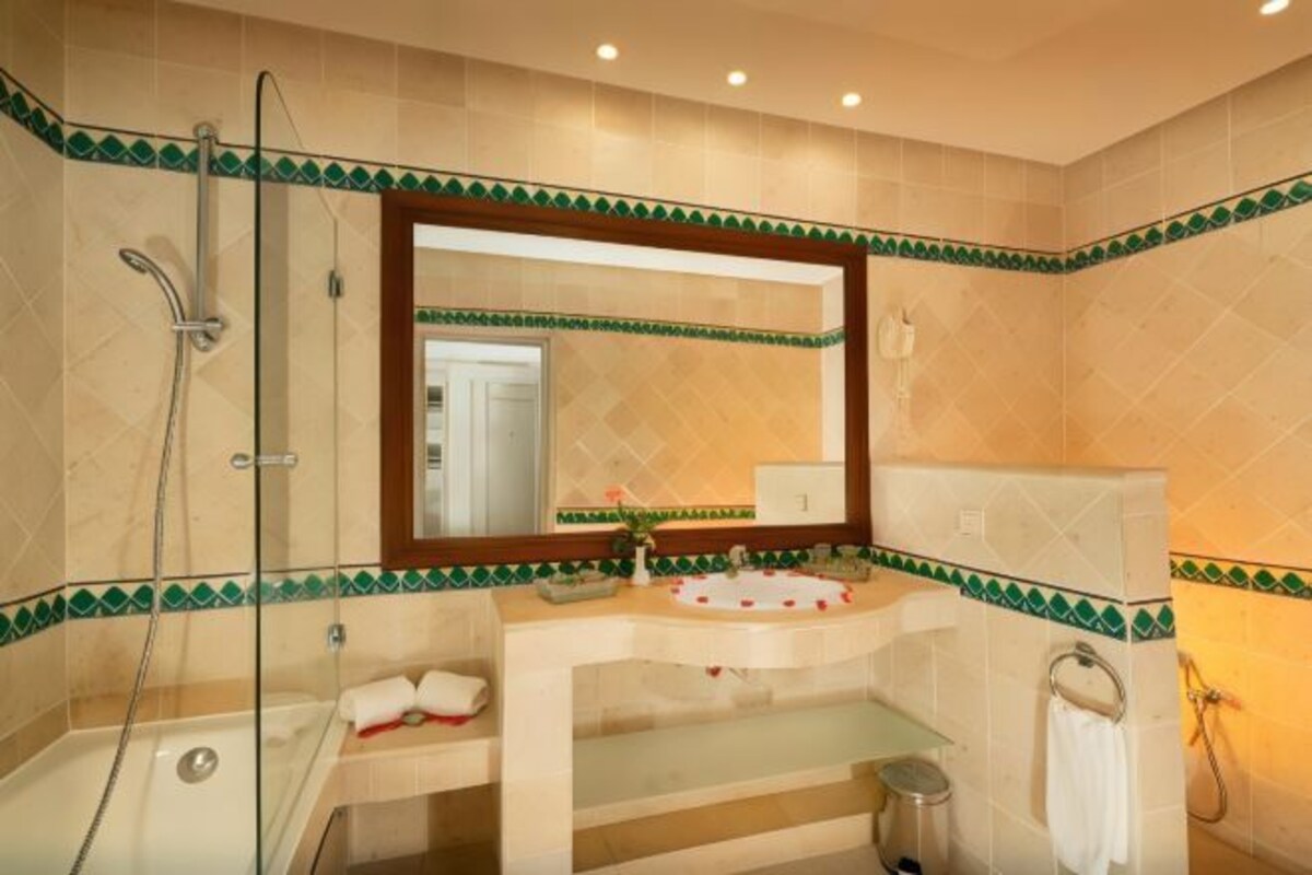 A bathroom with a glass shower enclosure, a sink with a mirror, and a towel rack.
