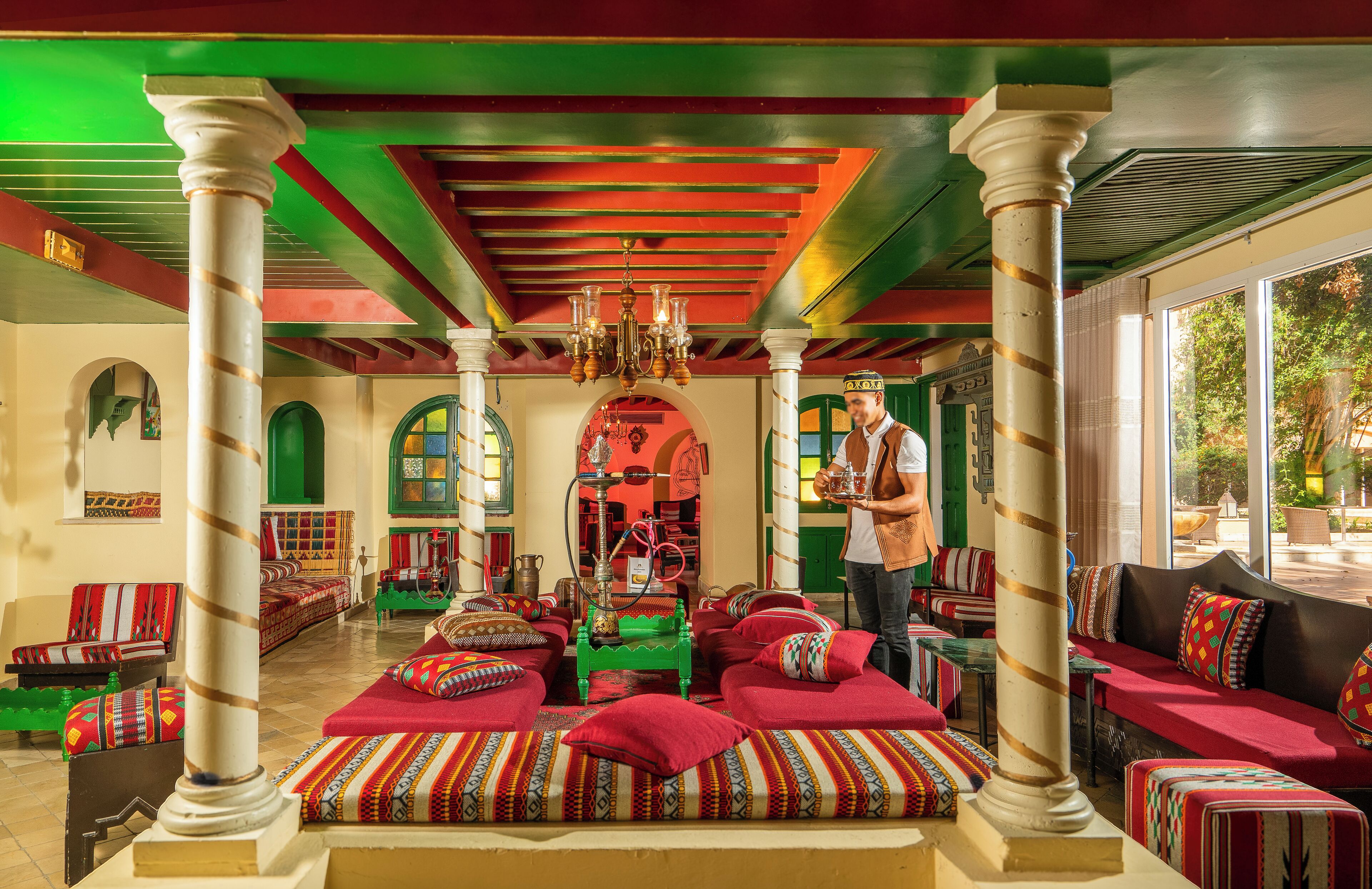 Un intérieur chaleureux avec un espace salon central, des arches vertes et un lustre.