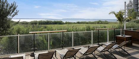 A deck with outdoor seating and a view of a body of water.