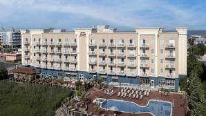 A hotel with multiple balconies, a swimming pool, and a view of the ocean.