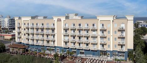 A hotel with multiple balconies, a swimming pool, and a view of the ocean.