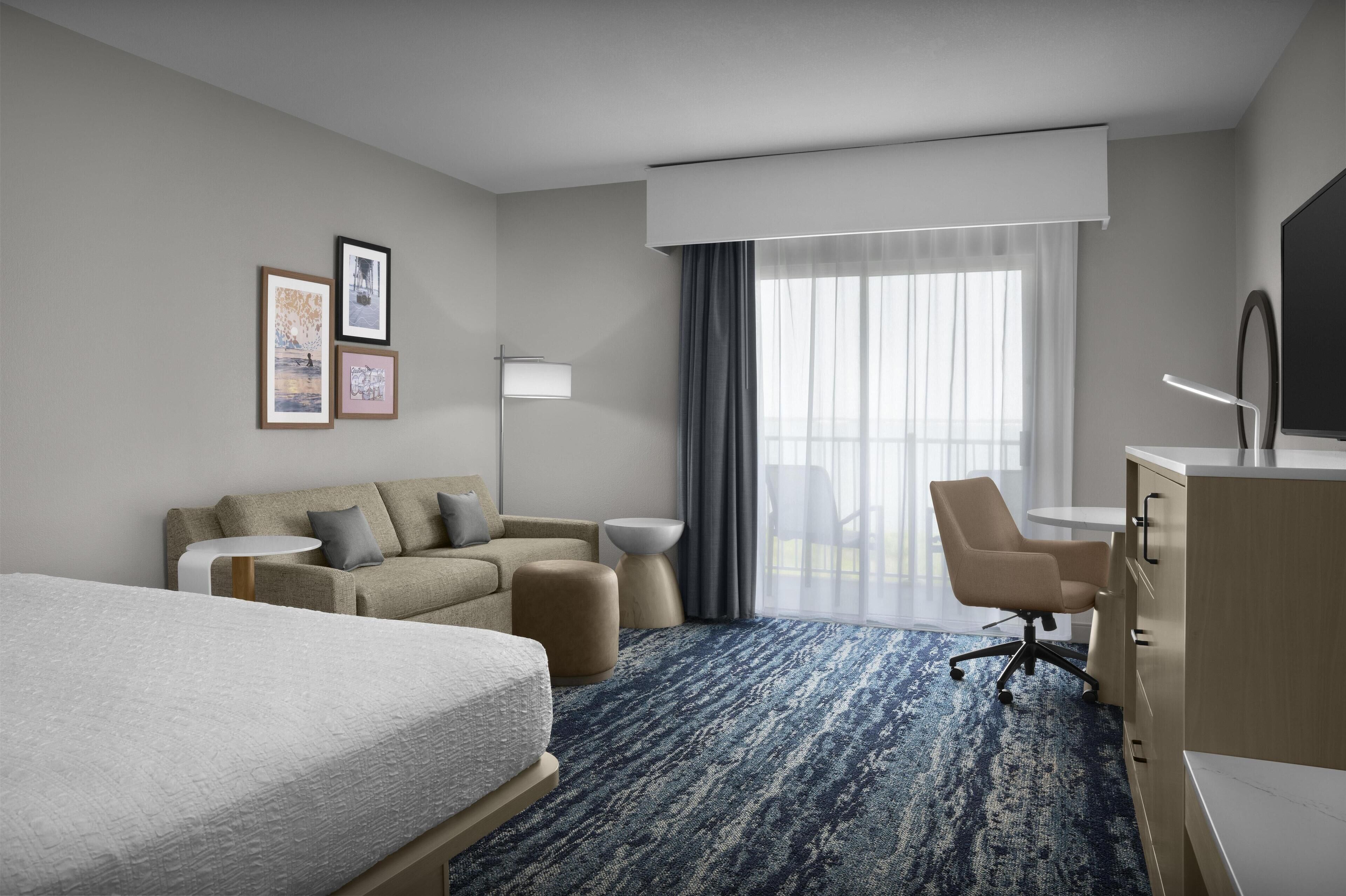 Ein Hotelzimmer mit einem Bett, einer Couch, einem Schreibtisch und einem Sessel.
