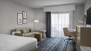 Ein Hotelzimmer mit einem Bett, einer Couch, einem Schreibtisch und einem Sessel.