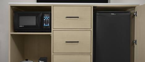 Una cocina equipada con microondas, refrigerador y tres cajones.