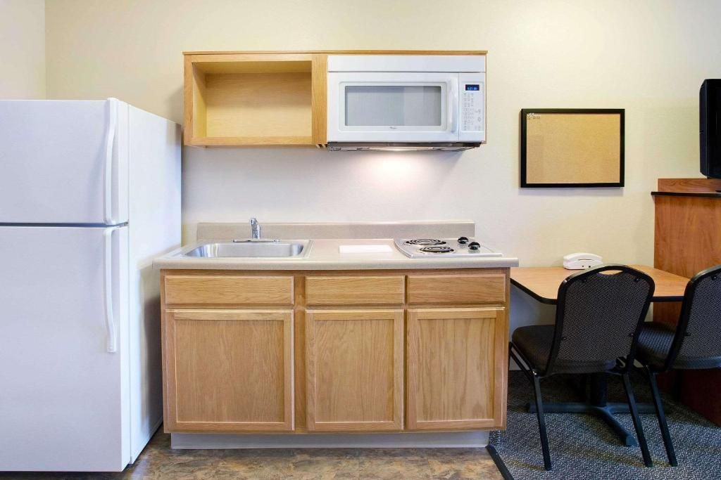 A compact kitchenette with a microwave, a refrigerator, a sink, and a small dining area with two chairs.