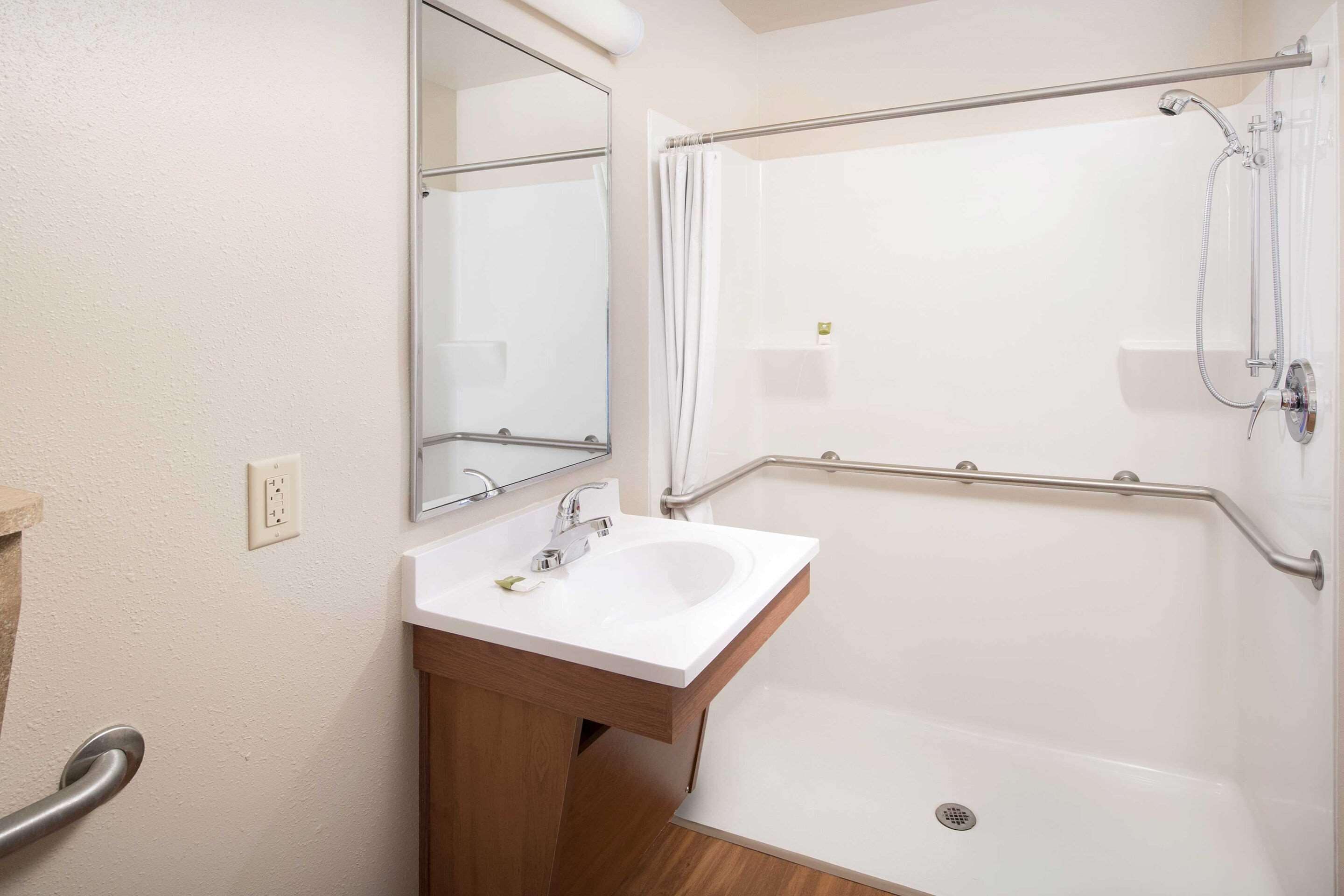 A bathroom with a white sink, mirror, and shower.