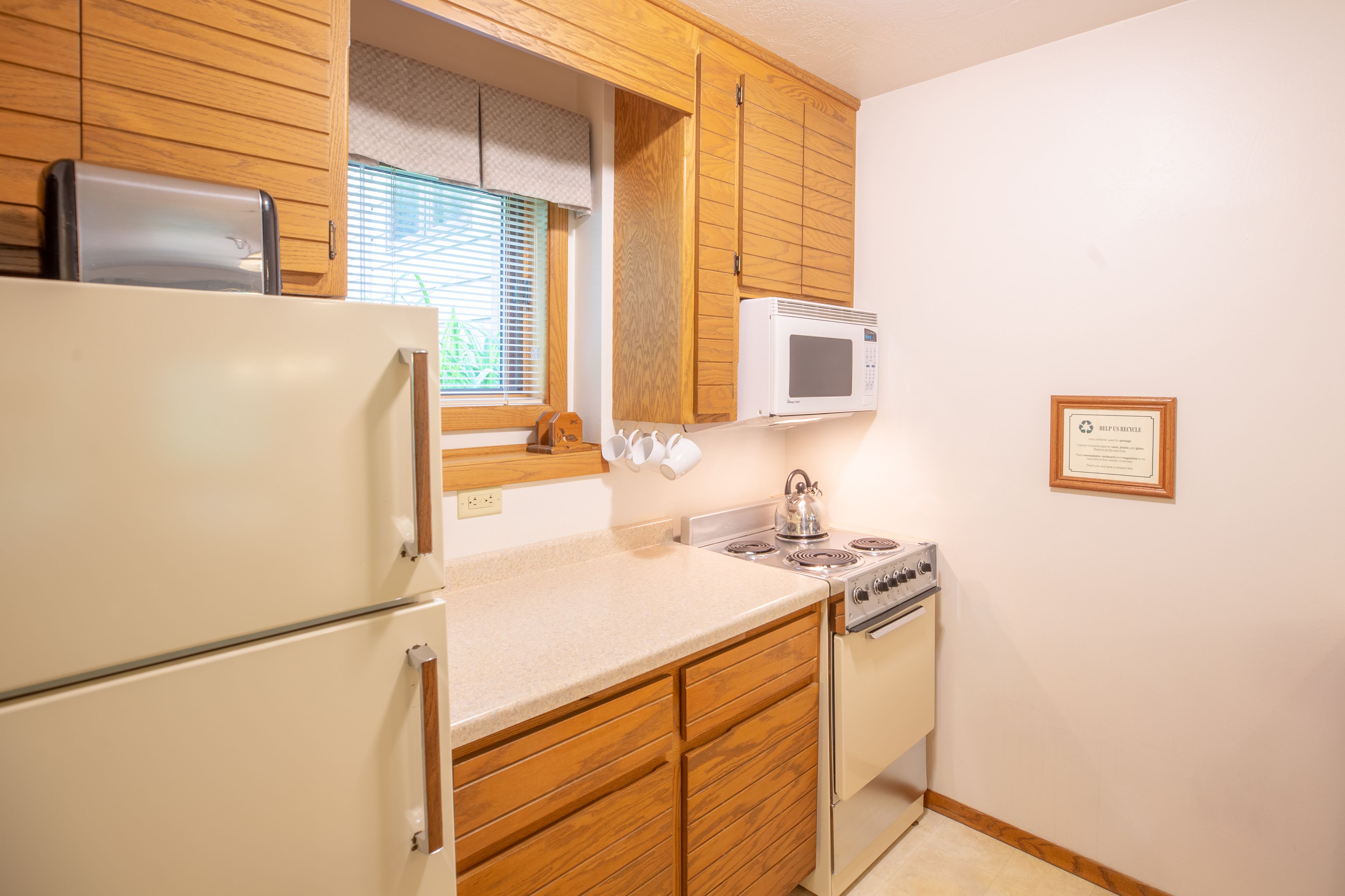 A kitchen with wooden cabinets, a white refrigerator, a microwave, and a stove.