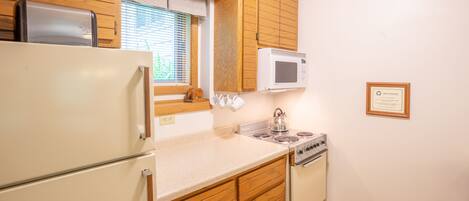 A kitchen with wooden cabinets, a white refrigerator, a microwave, and a stove.