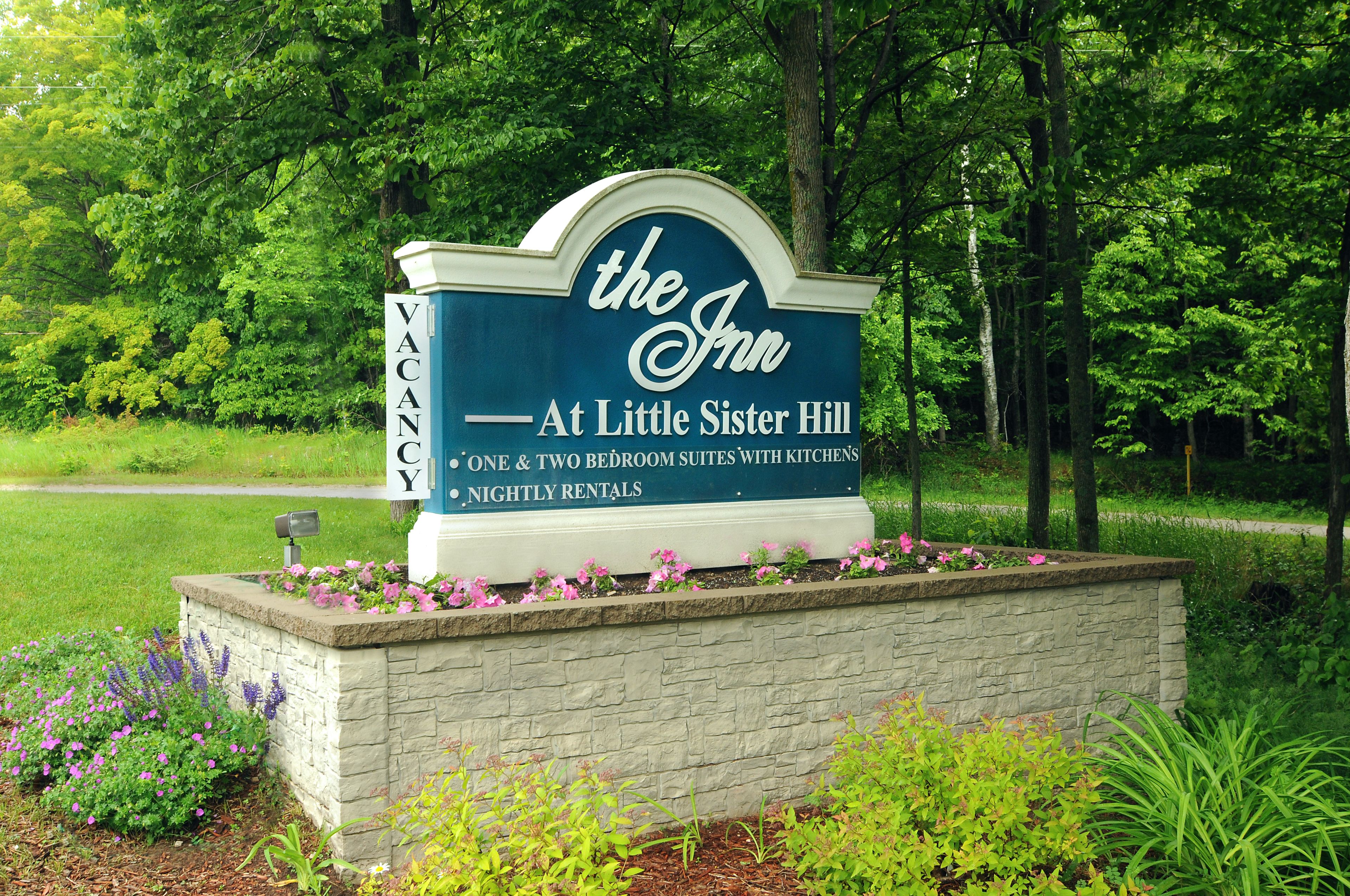 A sign for 'The Inn' at Little Sister Hill, indicating availability of one and two bedroom suites with kitchens and offering nightly rentals.