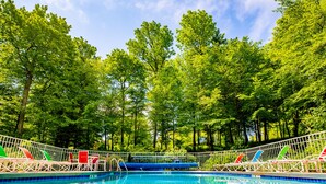 A swimming pool surrounded by trees and a white fence with lounge chairs. - The Inn at Little Sister Hill (Sister Bay)