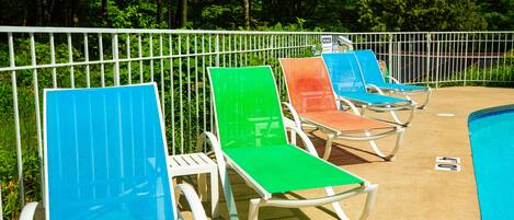 Un área junto a la piscina con sillones de descanso y una cerca.