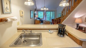 A kitchen with a stainless steel sink, a coffee maker, and a microwave. There is a wooden staircase in the background. - The Inn at Little Sister Hill (Sister Bay)
