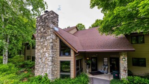 A stone and wood building with a covered porch and a pathway leading to the entrance. - The Inn at Little Sister Hill (Sister Bay)