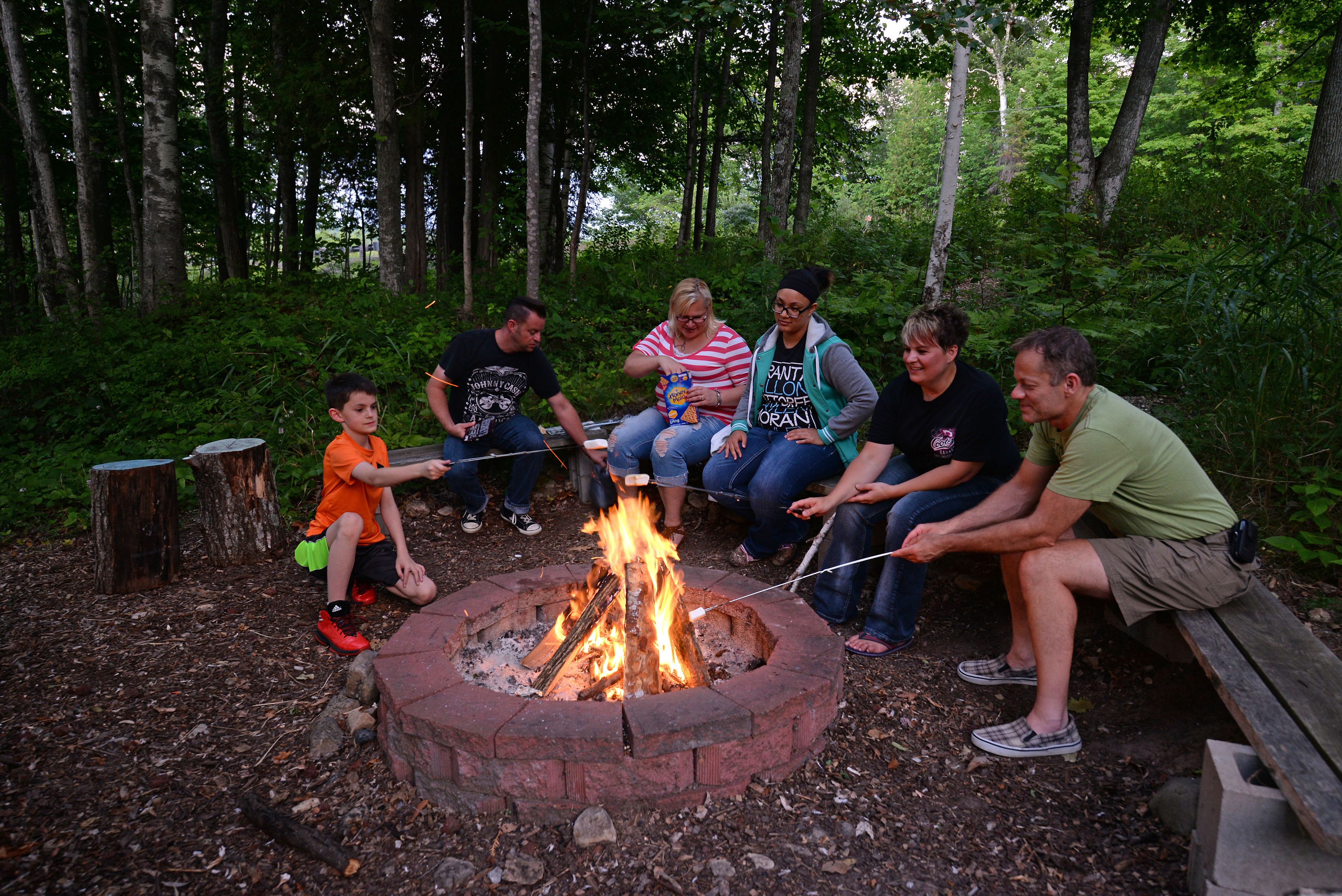 A group of people around a campfire in a wooded area.