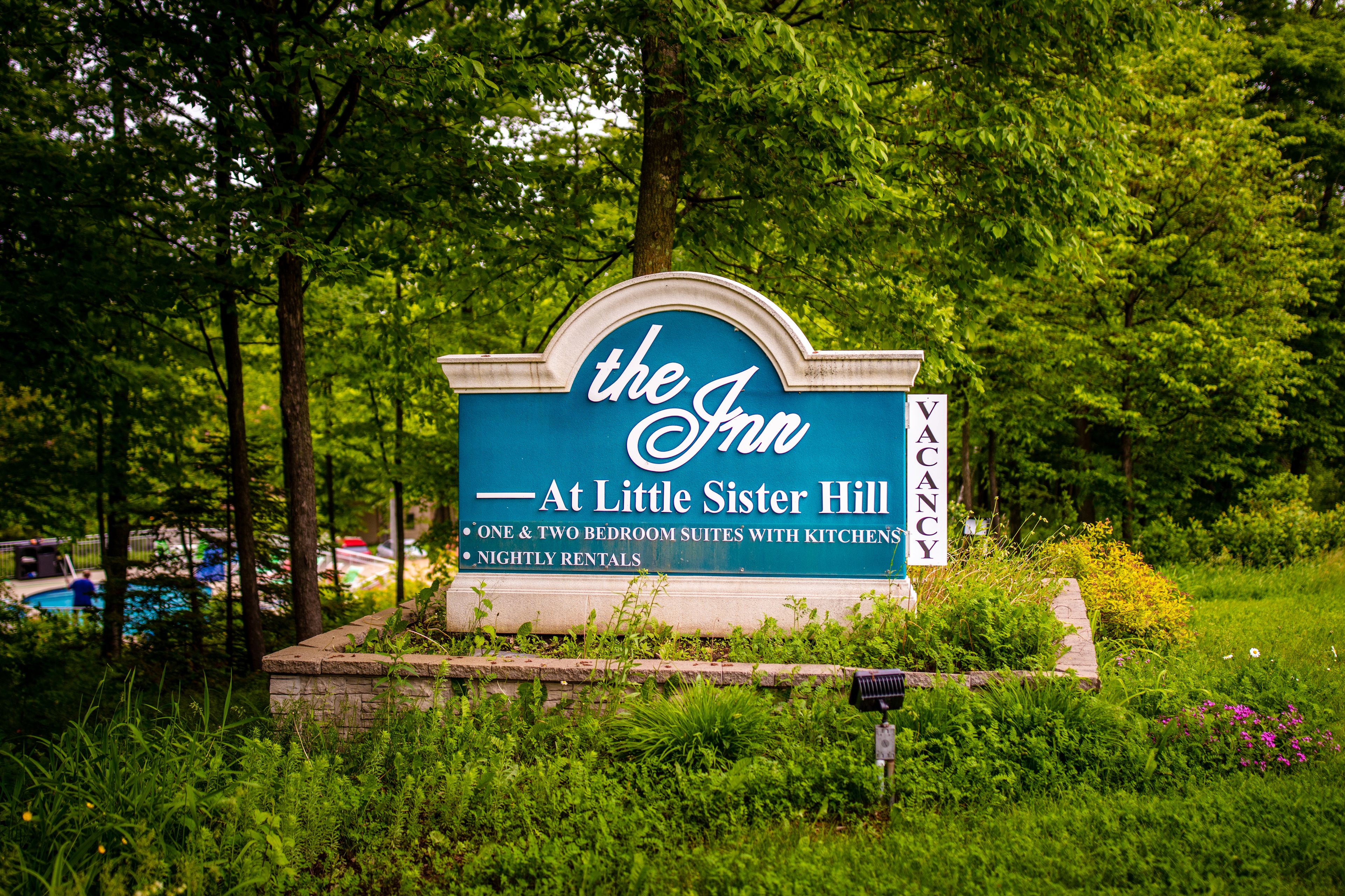 Un cartel que indica 'The Inn' en Little Sister Hill, con suites de uno y dos dormitorios, cocinas y alquileres por noche.