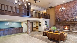 A spacious lobby with a reception desk, a fireplace, and a seating area. - The Watford (Watford City)