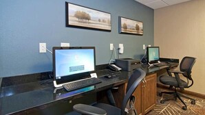 A hotel reception desk with two computer monitors, a keyboard, a mouse, and a chair. - The Watford (Watford City)