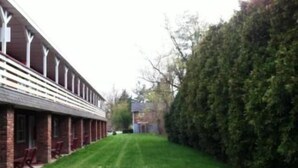 A building with a long, covered outdoor area with benches. - Waterford Inns on the Hudson (Waterford)