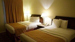 A hotel room with two single beds, each with a wooden headboard, a bedside table with a lamp, and a telephone. - Waterford Inns on the Hudson (Waterford)