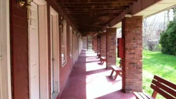 A covered corridor with benches and a brick wall. - Waterford Inns on the Hudson (Waterford)