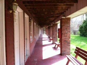 A covered corridor with benches and a brick wall. - Waterford Inns on the Hudson (Waterford)