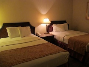 Ein Hotelzimmer mit zwei Betten, einem Nachttisch mit Lampe und einem Telefon.
