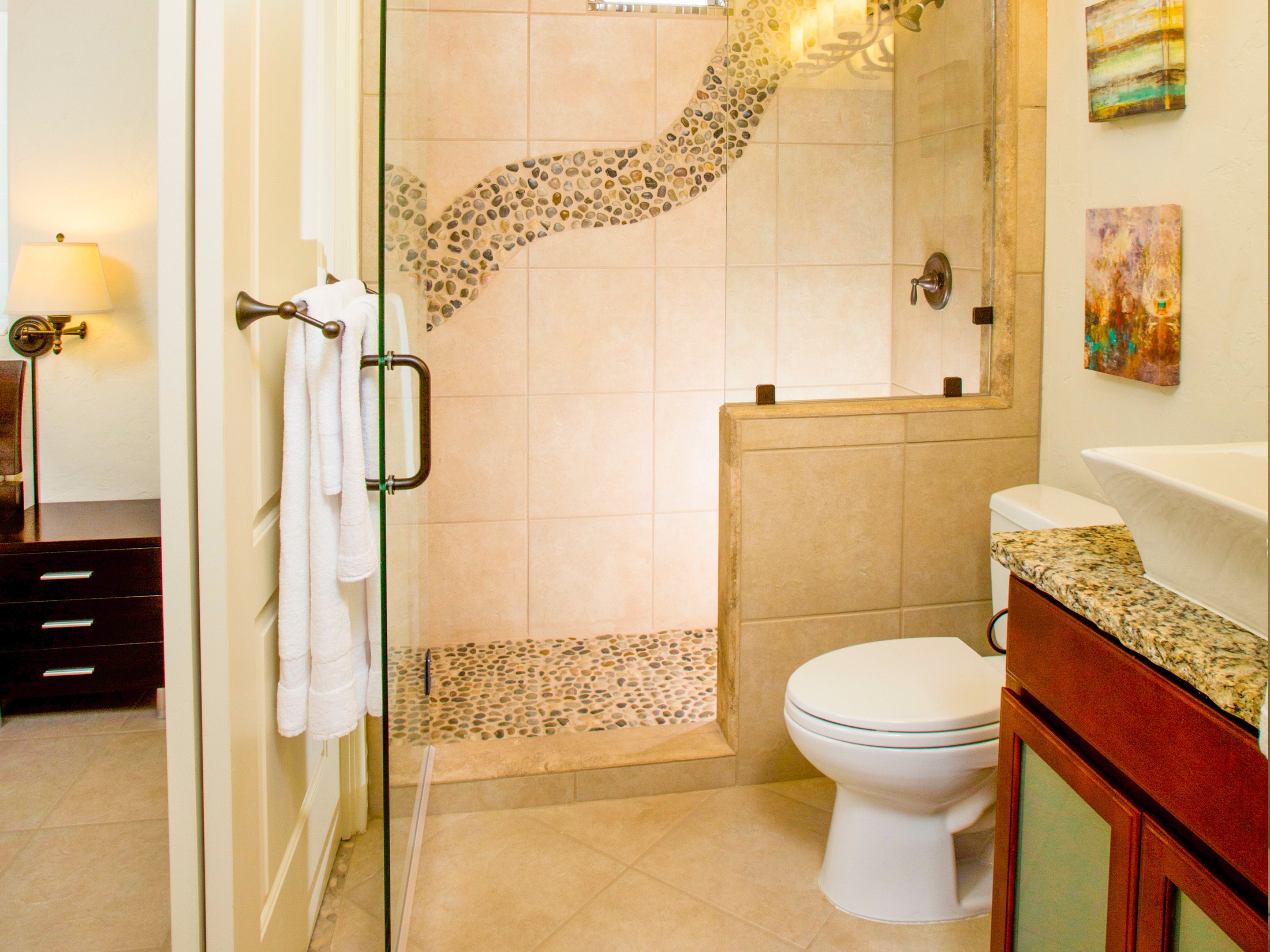 Ein Badezimmer mit Glasdusche, Toilette und Waschbecken mit Granitplatte.