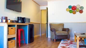 Un ambiente compatto con angolo cottura, una TV a schermo piatto montata a parete, un elemento decorativo e un pavimento in legno.