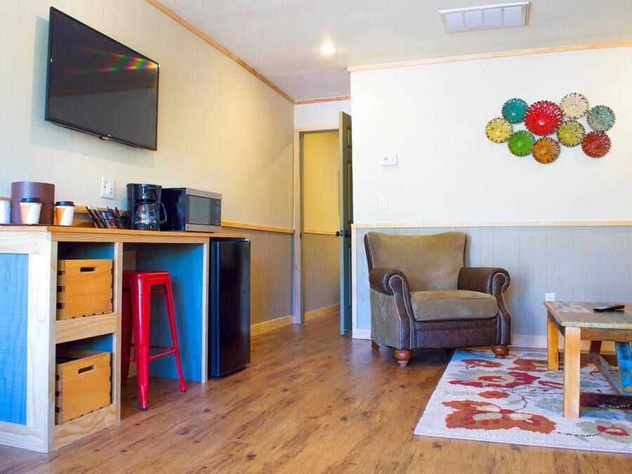 Un ambiente compatto con angolo cottura, una TV a schermo piatto montata a parete, un elemento decorativo e un pavimento in legno.